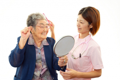caregiver showing mirror to senior woman